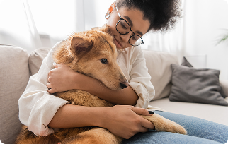 Woman hugging her dog on a sofa at home.